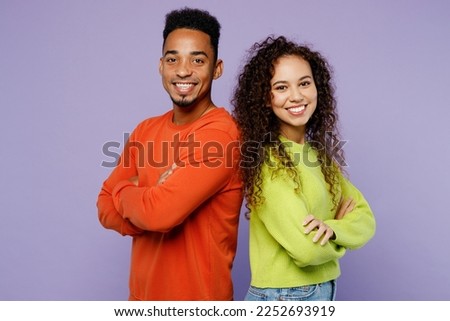 Side view young couple two friends family man woman of African American ethnicity wear casual clothes together stand back to back hold hands crossed folded isolated on pastel plain purple background