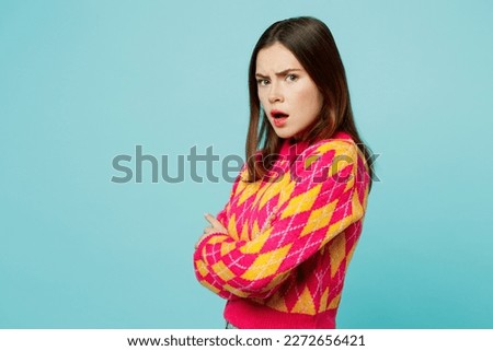 SIde view young dissatisfied caucasian woman wears bright casual clothes hold hands crossed folded look camera isolated on plain pastel light blue cyan background studio portrait. Lifestyle concept