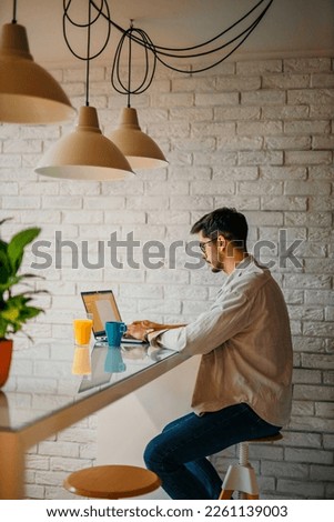 Side view of a young fashionable man working at home. Photo series of Caucasian man working from home as a freelancer.