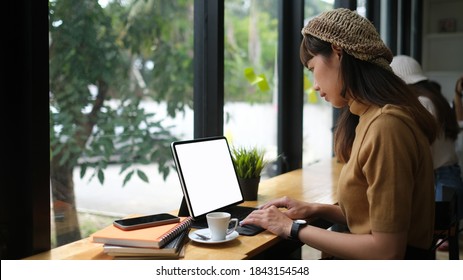 Side View Of Young Female Free Lancer Working On Digital Tablet While Sitting In Meeting Room.