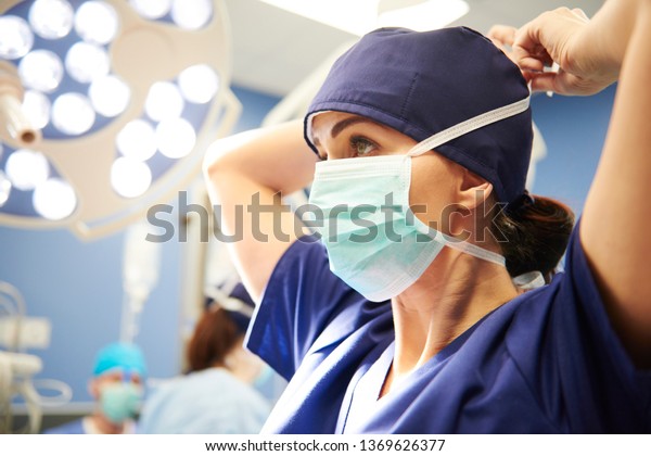 手術用マスクを結ぶ若い女性外科医の側面図 の写真素材 今すぐ編集