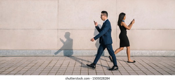 Side view of young formal business people addicted to smartphones while walking down street in sunlight being inattentive to each other - Shutterstock ID 1505028284