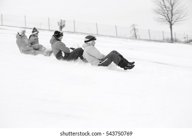 Side view of young friends sledging on snow covered slope