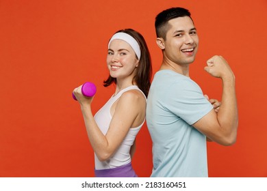 Side view young fun fitness trainer instructor sporty two man woman in headband t-shirt hold dumbbells show muscles spend weekend in home gym isolated on plain orange background Workout sport concept - Powered by Shutterstock