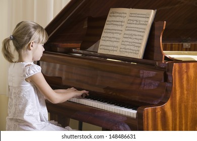 Side view of a young girl playing the piano