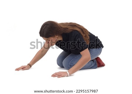  side view a young girl who is on her knees on the floor looking for something on a white background