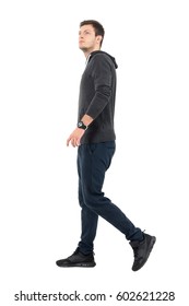 Side View Of Young Handsome Sporty Man In Sweatshirt And Sweat Pants Walking Looking Up. Full Body Length Portrait Over White Studio Background.