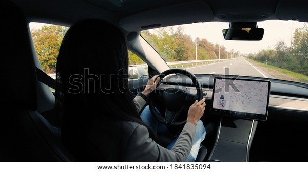 Side view of young happy Caucasian woman\
traveling in self-driving electric car and dancing. Beautiful\
female going in autonomous driverless vehicle and making moves.\
Close up. Autopilot\
concept