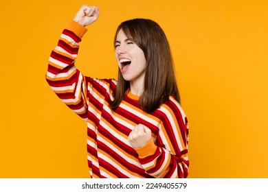 Side view young happy excited overjoyed woman 20s in red striped sweatshirt doing winner gesture celebrate clenching fists say yes isolated on plain yellow background studio. People lifestyle concept - Shutterstock ID 2249405579