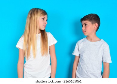 Side view of young happy smiling two kids boy and girl standing over blue studio background