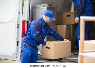 Side View Of A Young Man Carrying Cardboard Box From Truck