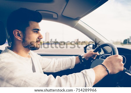 Side view of a young man is driving a car with a security position