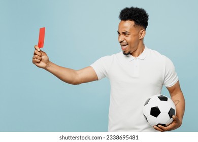 Side view young man fan wear basic t-shirt cheer up support football sport team hold soccer ball, red card propose player retire from field watch tv live stream isolated on plain blue color background - Powered by Shutterstock