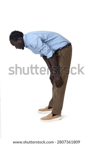side view of a young man standing hunched looking down on a white background