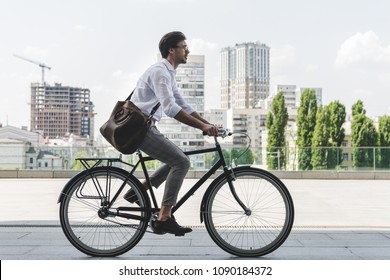 Side View Of Young Man In Stylish Clothes Riding Vintage Bicycle On City Street