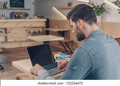 Side View Of Young Man Using Laptop While Sitting At Table In Cafe