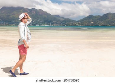 Side View Of A Young Man Walking On The Beach Of Seychelles