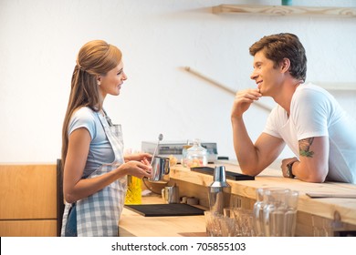 Side View Of Young Man And Woman Flirting And Smiling Each Other While Working N Cafe