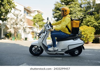 Side view of young man working as courier riding on motorcycle