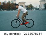 Side view young modern man cycling on a classic bike on the city road. Copy space. Active and ecological lifestyle concept