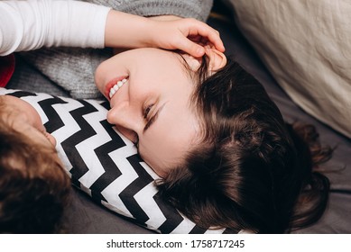 Side View Of Young Mother Lying In Tent Relaxing With Little Daughter, Smiling Mom Rest Take, Enjoy Calm Weekend In Child Room, Spend Time Together. Relative People Family Concept. Selective Focus