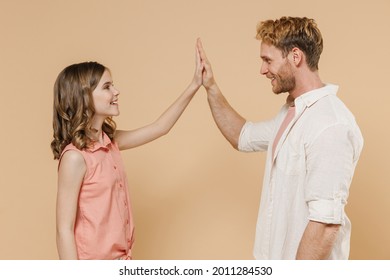 Side View Young Parent Man Have Fun With Child Teen Girl In Casual Pastel Clothes Daddy Little Kid Daughter Greeting Giving High Five Isolated On Beige Background. Father's Day Love Family Concept.