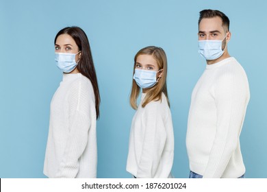 Side view of young parents mom dad with child kid daughter teen girl in sweaters sterile face mask safe from coronavirus virus covid-19 isolated on blue background. Family day parenthood concept