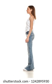 Side View Of Young Pretty Woman Posing In Bell Bottom Jeans On White Background