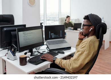 Side View Of Young Serious Lack Man Concentrating On Decoding Data While Sitting In Front Of Computer Monitor By Workplace In Office