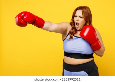 Side view young serious strict chubby overweight plus size big fat fit woman wear blue top red gloves warm up train boxing isolated on plain yellow background studio home gym. Workout sport concept - Powered by Shutterstock