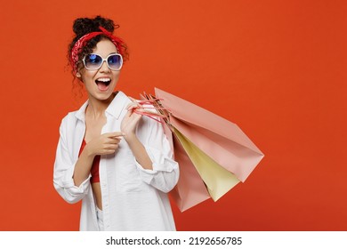 Side view young shocked woman of African American ethnicity wear white shirt top hold package bags with purchases after shopping look aside isolated on plain orange background People lifestyle concept