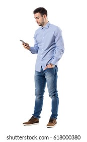 Side View Of Young Smart Casual Business Man Reading Message On Cell Phone. Full Body Length Portrait Isolated Over White Background.