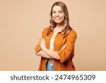 Side view young smiling Caucasian woman she wear orange shirt casual clothes hold hands crossed folded look camera isolated on plain pastel light beige background studio portrait. Lifestyle concept