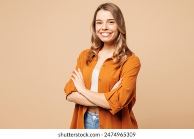 Side view young smiling Caucasian woman she wear orange shirt casual clothes hold hands crossed folded look camera isolated on plain pastel light beige background studio portrait. Lifestyle concept - Powered by Shutterstock