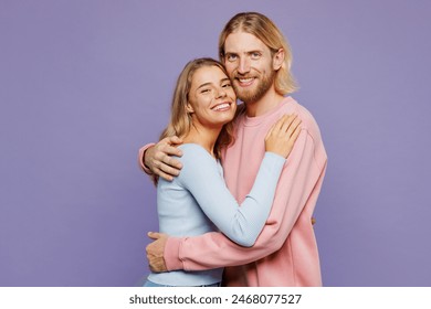 Side view young smiling fun couple two friends family man woman wear pink blue casual clothes together hug cuddle embrace look camera isolated on pastel plain light purple background studio portrait