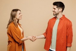Side View Young Smiling Happy Couple Two Friends Family Man Woman Wear Casual Clothes Looking To Each Other Shaking Hands Together Isolated On Pastel Plain Light Beige Color Background Studio Portrait