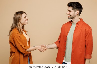 Side view young smiling happy couple two friends family man woman wear casual clothes looking to each other shaking hands together isolated on pastel plain light beige color background studio portrait - Powered by Shutterstock