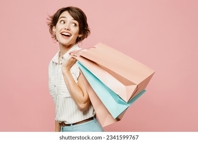 Side view young smiling woman wears casual clothes hold shopping paper package bags look aside on area isolated on plain light pastel pink color background studio. Black Friday sale buy day concept - Powered by Shutterstock