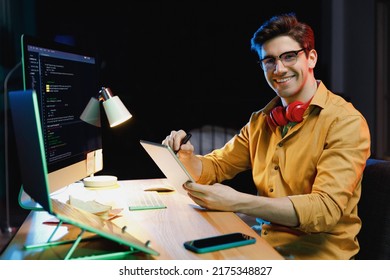 Side view young software engineer IT specialist programmer man in shirt work at home writing code script on laptop pc computer use tablet testing game over level interface. Program development concept