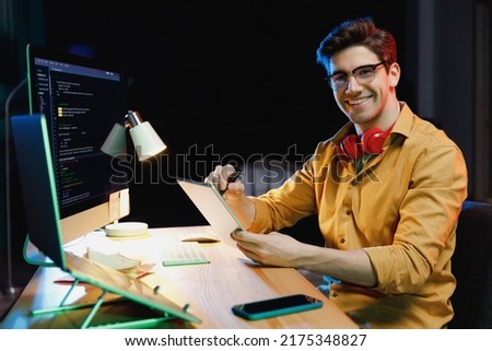 Side view young software engineer IT specialist programmer man in shirt work at home writing code script on laptop pc computer use tablet testing game over level interface. Program development concept