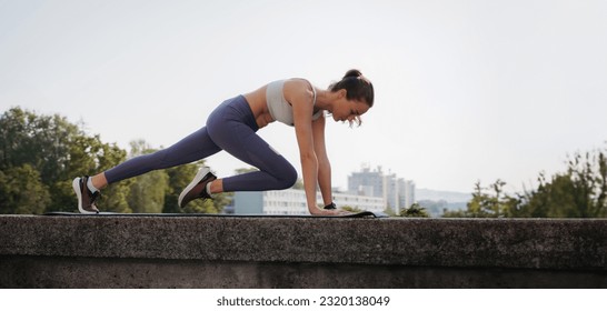 Side view of young sporty woman doing mountain climbers on gym mat in the city. - Shutterstock ID 2320138049