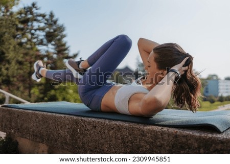 Side view of young sporty woman doing bicycle crunches on gym mat in the city.