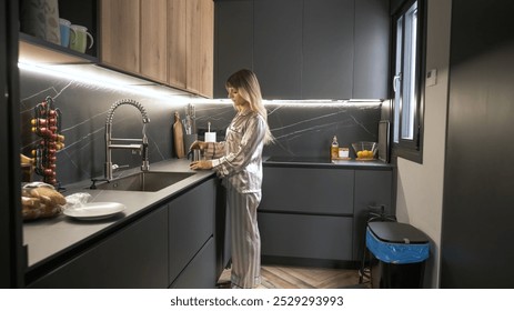 Side view of young transgender woman in nightwear using coffee pot at modern kitchen counter during morning - Powered by Shutterstock