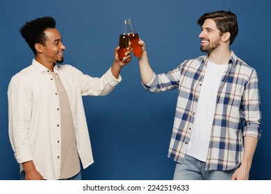 Side view young two friends happy cheerful fun men wear casual shirts together talk speak spent time in bar drink beer alcohol hug raise up clink bottles isolated plain dark royal navy blue background - Powered by Shutterstock