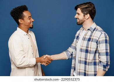 Side view young two friends cheerful men 20s wear white casual shirts looking camera together shaking hands meeting each other isolated plain dark royal navy blue background. People lifestyle concept - Powered by Shutterstock