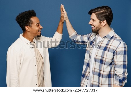Side view young two friends men wear white casual shirts meet together greeting giving high five clapping hands folded together isolated plain dark royal navy blue background. People lifestyle concept