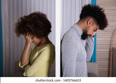 Side View Of Young Unhappy Couple Standing Back To Back At Home