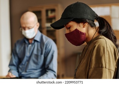 Side View Of Young Upset Woman In Protective Mask And Baseball Cap Sharing Her Traumatic Experience With Support Group At Session