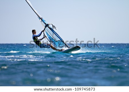 Side view of young windsurfer passing by
