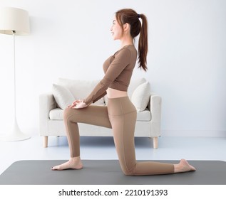 Side View Of Young  Woman In Activewear Doing Lunge Exercise While Having Workout At Home